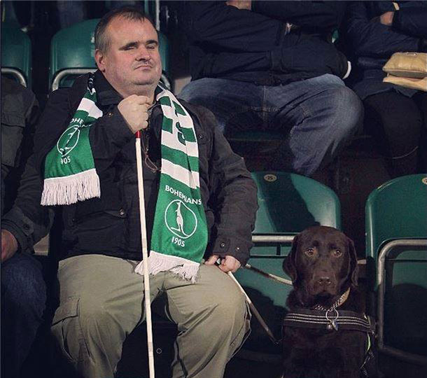 Homem aparentemente cego acompanha jogo com seu cão-guia 