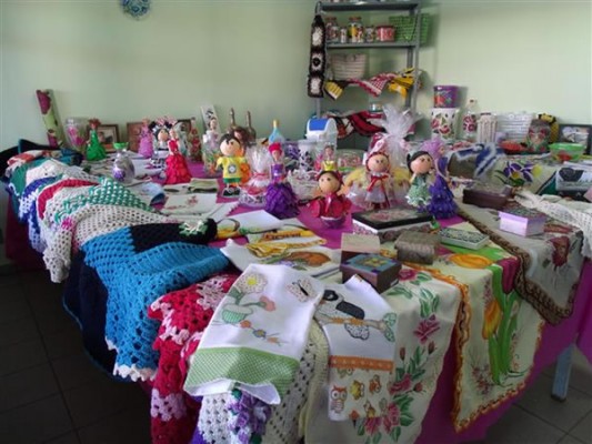 Artesanato como tapetes bordados e acessórios é vendido por preço acessível no final do curso