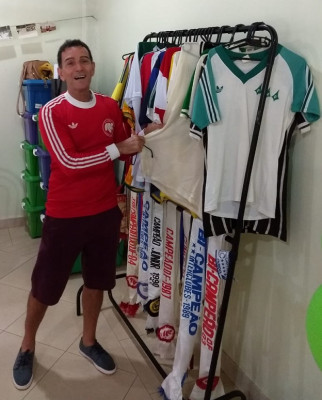 Ricardo ao lado das camisas dos clubes por onde passou e faixas de campeão